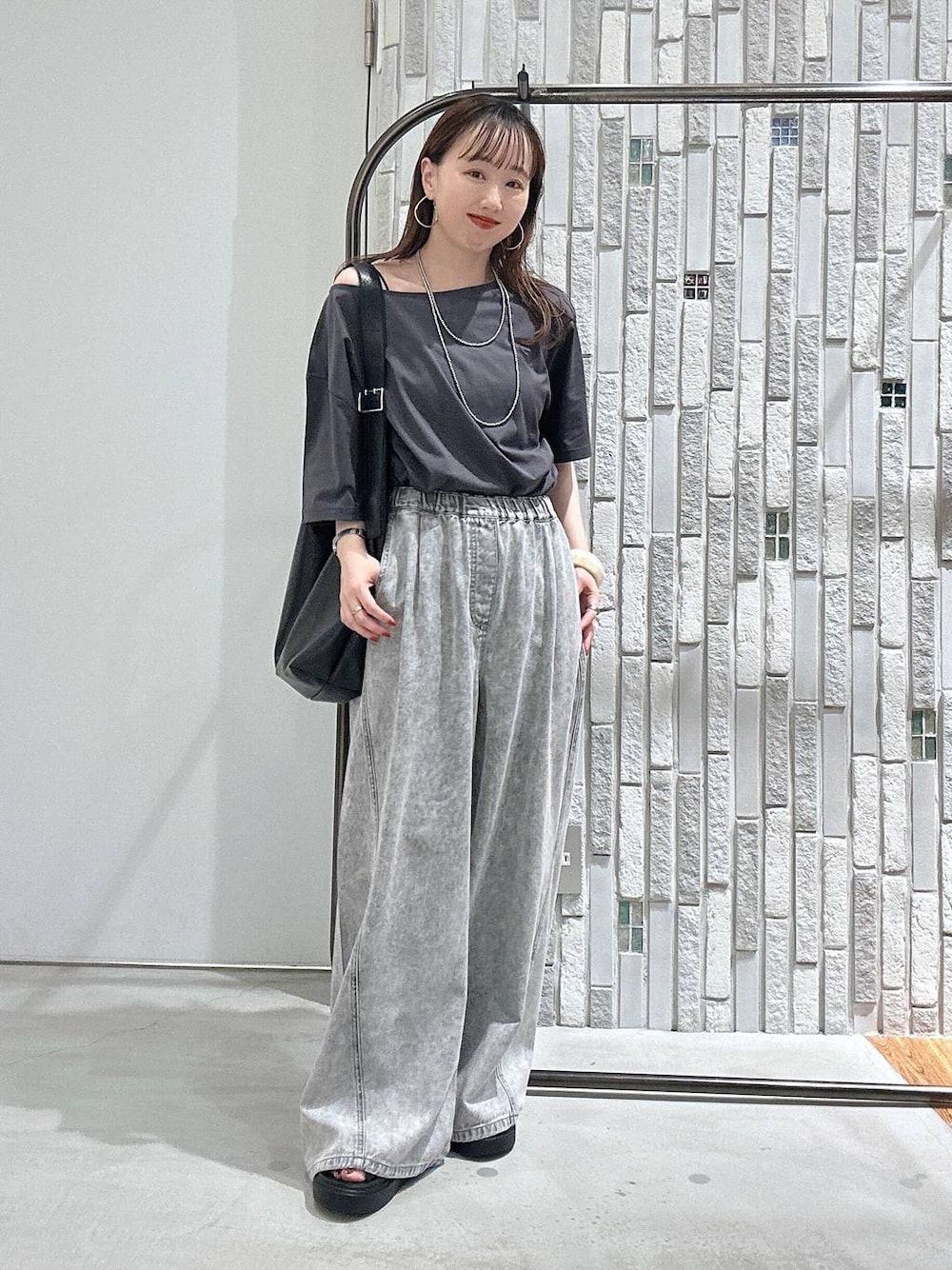 グレー系のTシャツ/カットソー、グレー系のデニムパンツ、ブラック系のサンダルを着用したレディースの春コーディネートの1枚目の写真