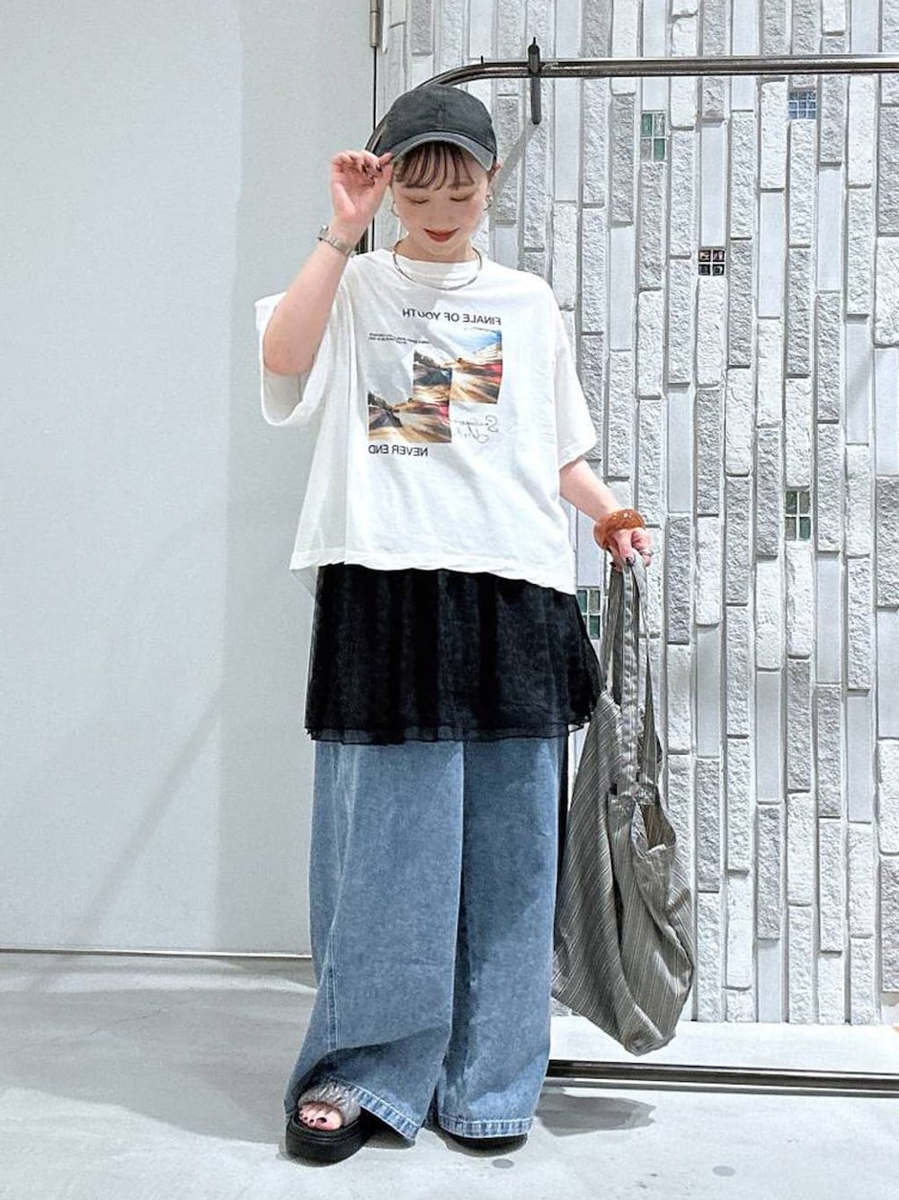 グレー系のトートバッグ、ホワイト系のTシャツ/カットソー、その他のサンダルを着用したレディースの夏コーディネートの1枚目の写真