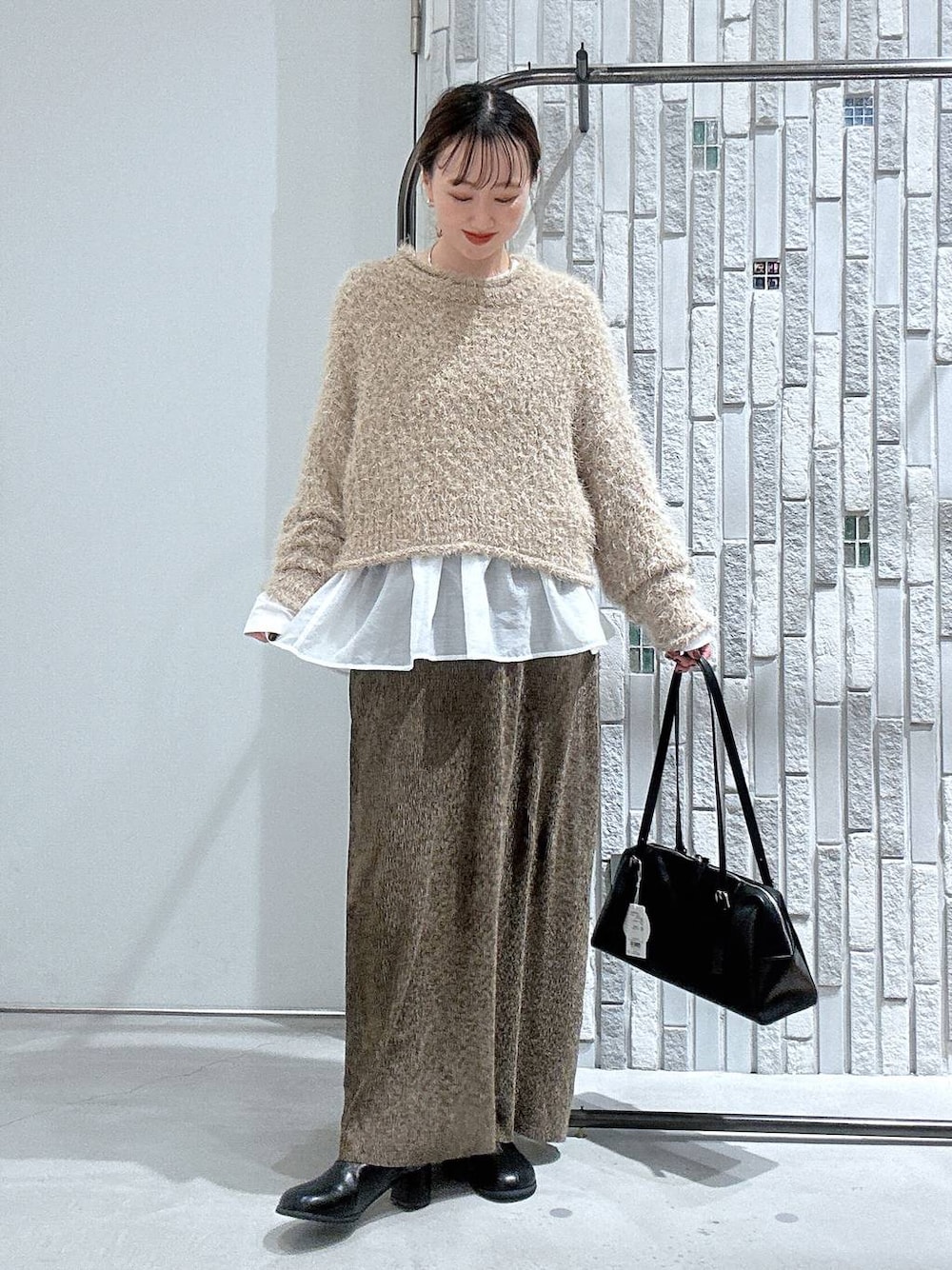 ブラック系のボストンバッグ、ホワイト系のTシャツ/カットソー、ブラック系のブーツを着用したレディースの冬コーディネートの1枚目の写真