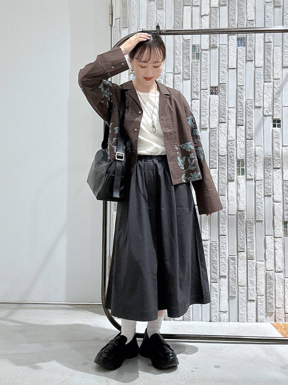 ブラウン系のシャツ/ブラウス、ブラウン系のローファー、ブラック系のショルダーバッグを着用したレディースの夏コーディネートの1枚目の写真