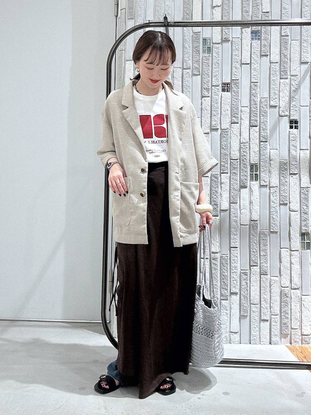 ブラウン系のスカート、ホワイト系のTシャツ/カットソー、ベージュ系のテーラードジャケットを着用したレディースの夏コーディネートの1枚目の写真