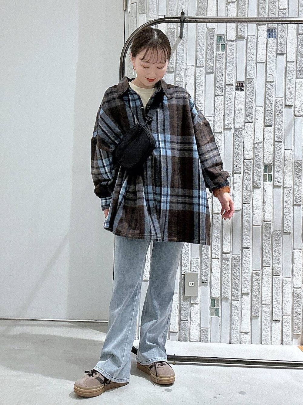 ブルー系のデニムパンツ、ブラック系のボディバッグ/ウエストポーチ、ブラウン系のシャツ/ブラウスを着用したレディースの秋コーディネートの1枚目の写真