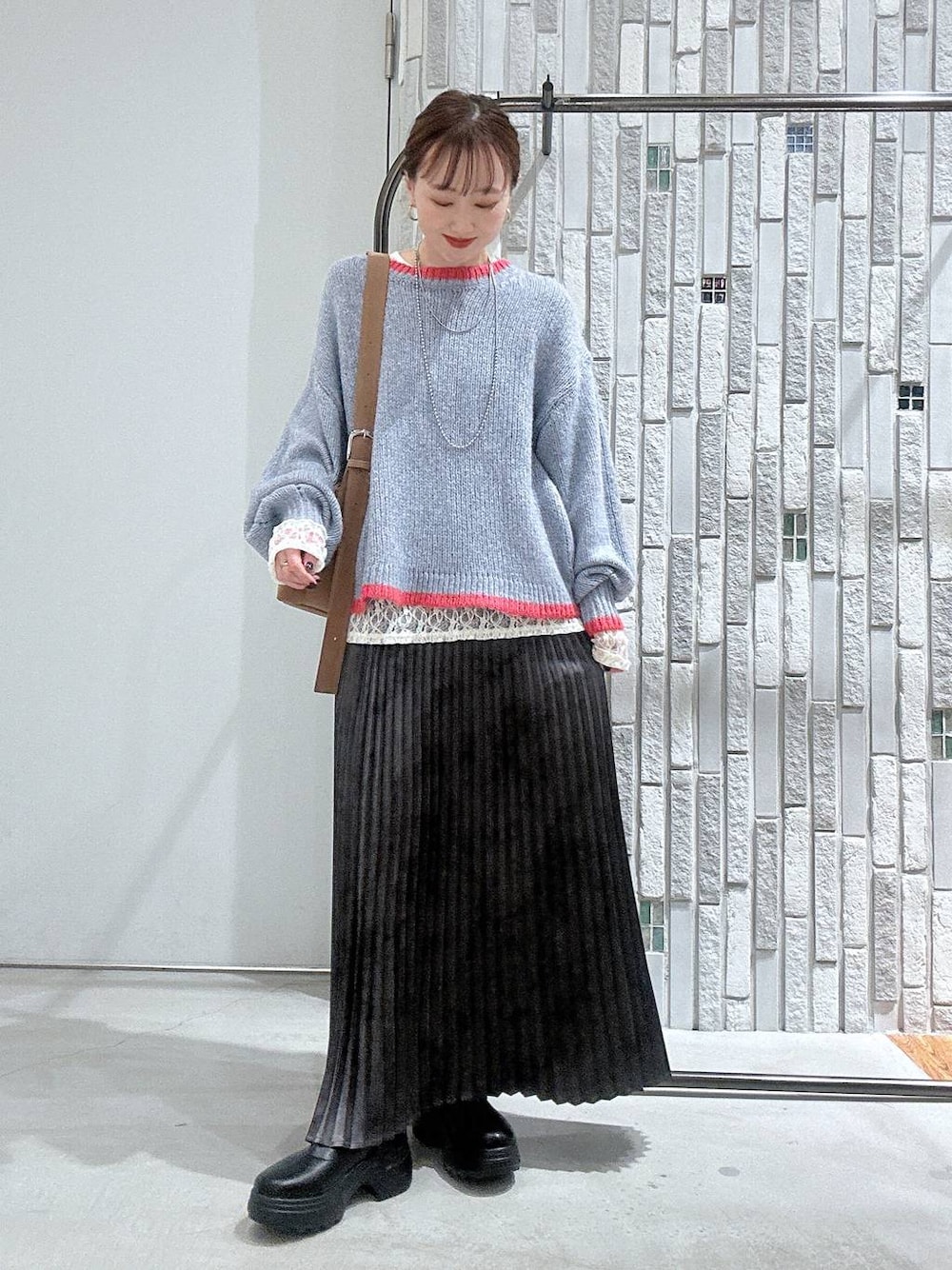 ブラウン系のショルダーバッグ、グレー系のスカート、ブラック系のブーツを着用したレディースの冬コーディネートの1枚目の写真