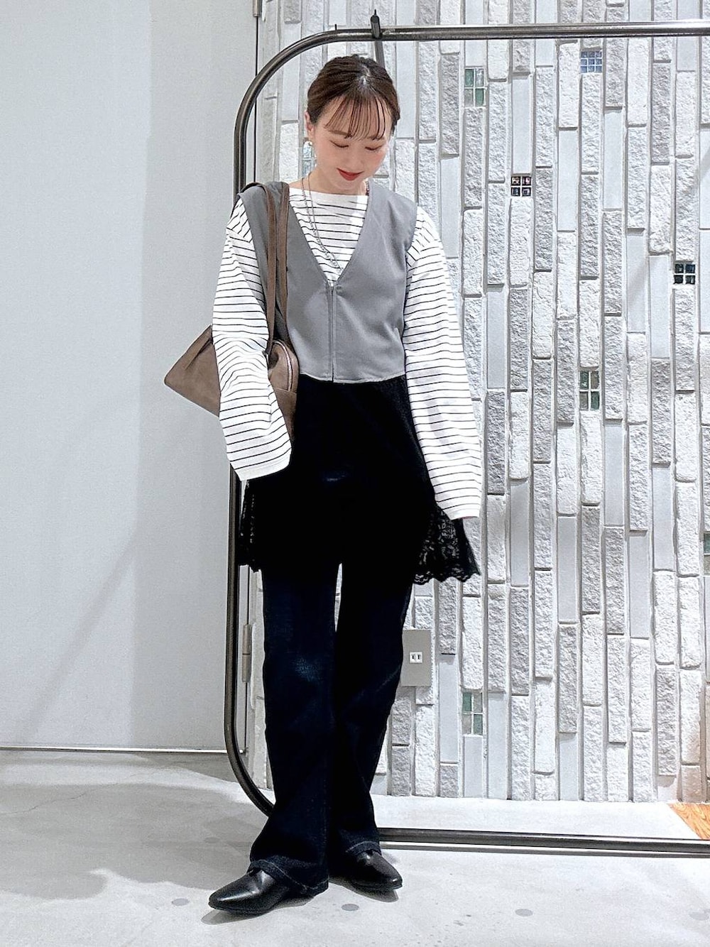 ブラウン系のボストンバッグ、ホワイト系のTシャツ/カットソー、ブルー系のデニムパンツを着用したレディースの冬コーディネートの1枚目の写真