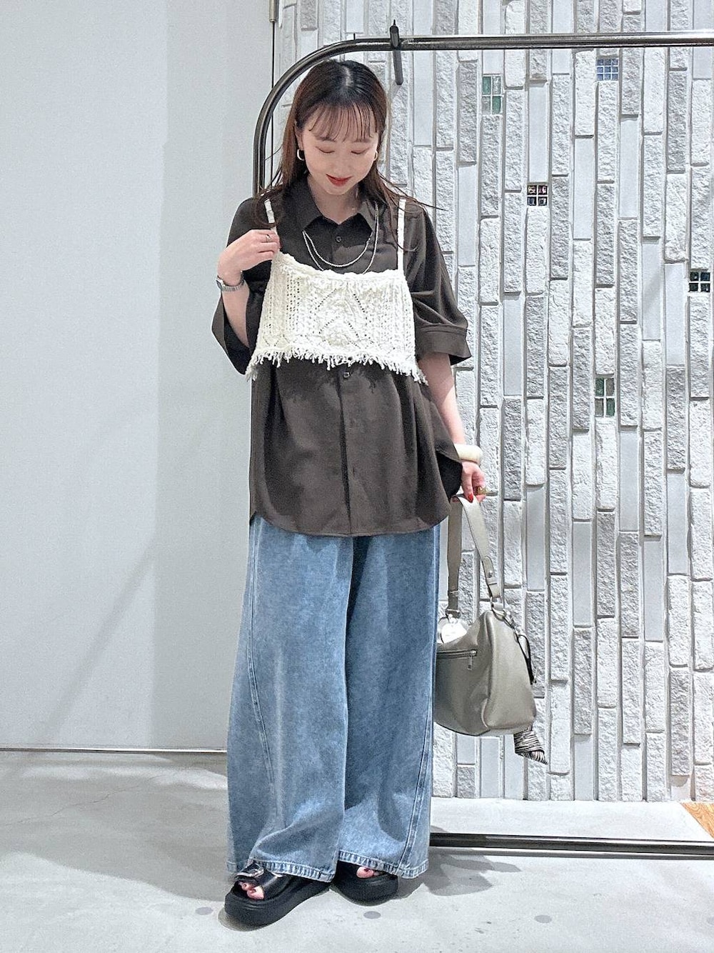 ブルー系のデニムパンツ、ブラック系のサンダル、ベージュ系のショルダーバッグを着用したレディースの春コーディネートの1枚目の写真