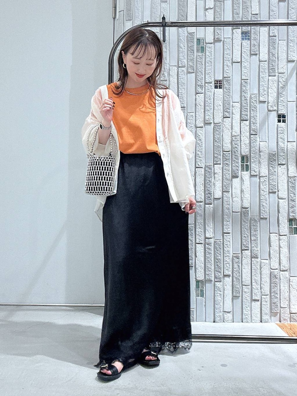 オレンジ系のTシャツ/カットソー、ベージュ系のシャツ/ブラウス、シルバー系のショルダーバッグを着用したレディースの夏コーディネートの1枚目の写真