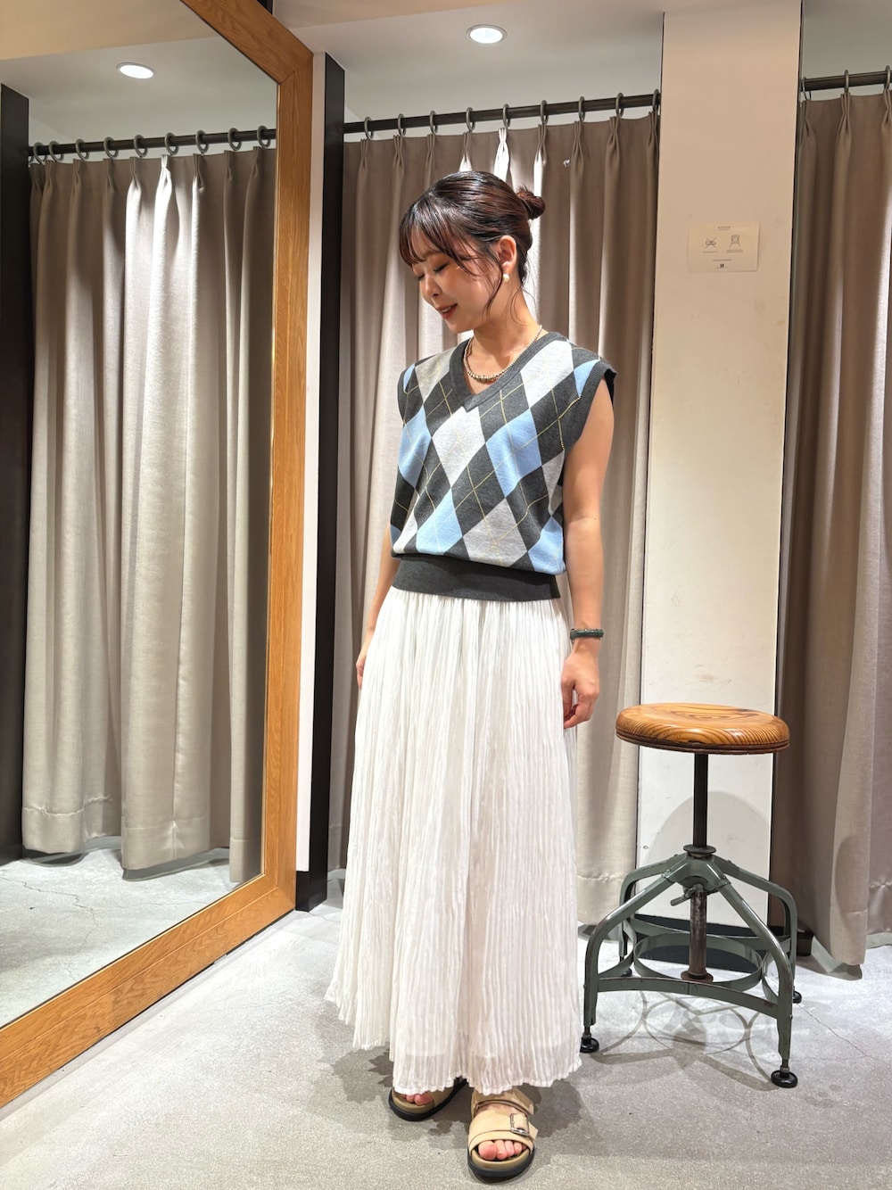 ベージュ系のサンダル、ホワイト系のスカート、グレー系のベストを着用したレディースの夏コーディネートの1枚目の写真