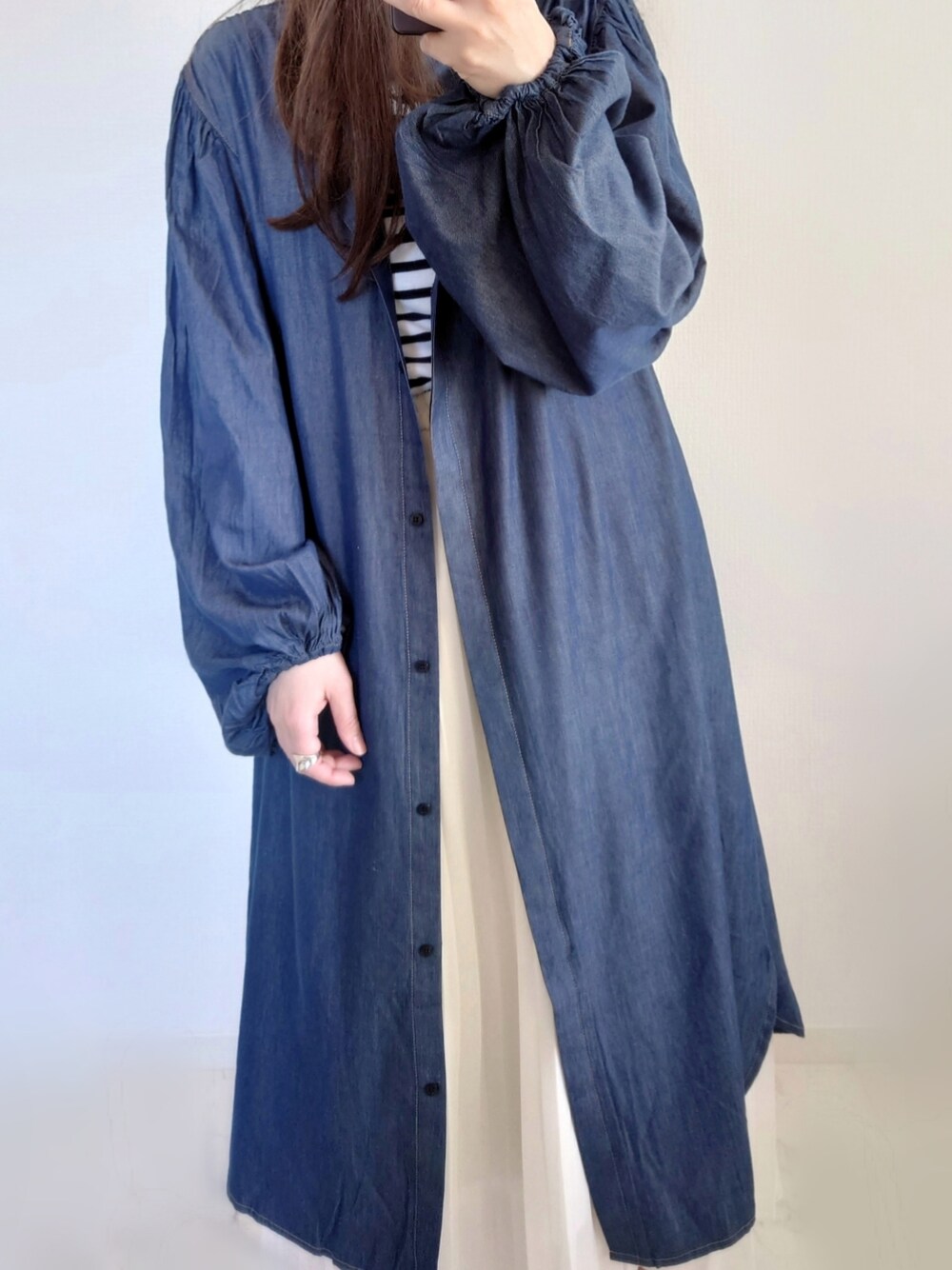 ブルー系のワンピース、グリーン系のショルダーバッグ、ホワイト系のTシャツ/カットソーを着用したレディースの冬コーディネートの2枚目の写真