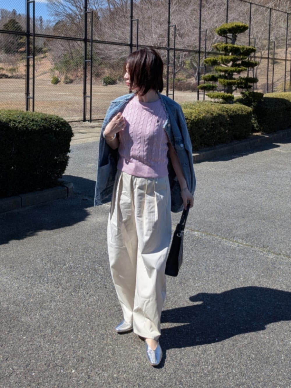 ピンク系のニット/セーター、ブルー系のデニムジャケット、ブラック系のショルダーバッグを着用したレディースの春コーディネートの1枚目の写真