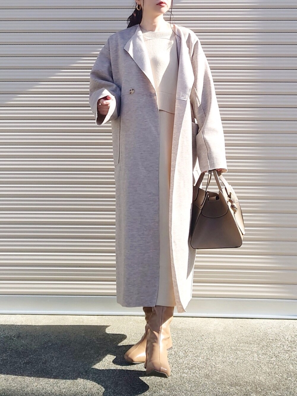 ベージュ系のワンピース、ホワイト系のノーカラーコート、ブラウン系のブーツを着用したレディースの冬コーディネートの2枚目の写真