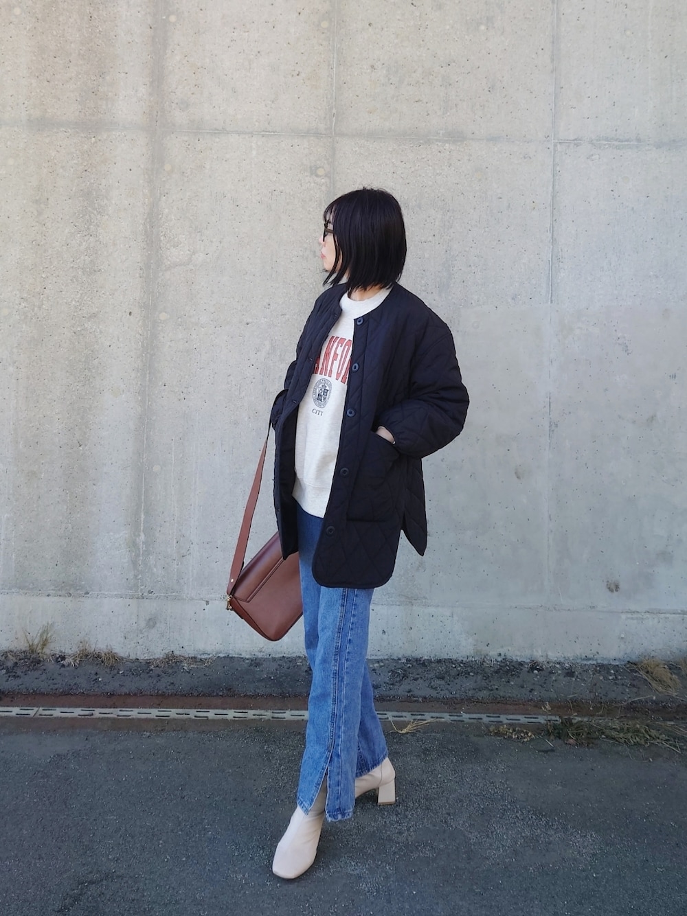 ベージュ系のスウェット、ブラック系のノーカラージャケット、ホワイト系のブーツを着用したレディースの冬コーディネートの1枚目の写真