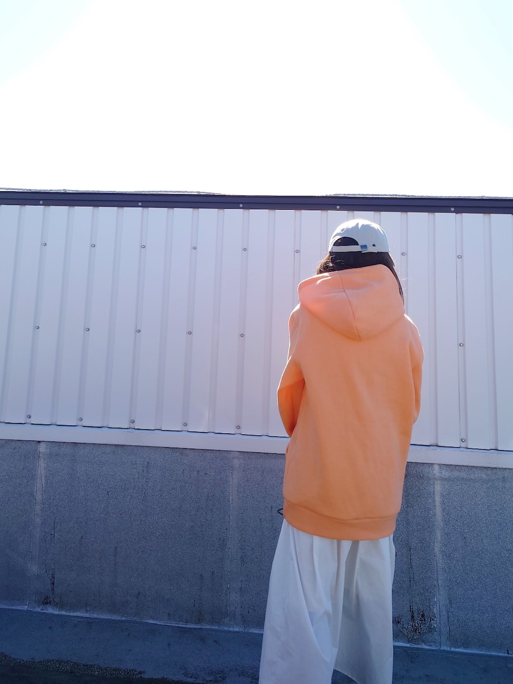 オレンジ系のパーカー、グリーン系のショルダーバッグ、ホワイト系のワンピース/ドレスを着用したレディースの春コーディネートの3枚目の写真