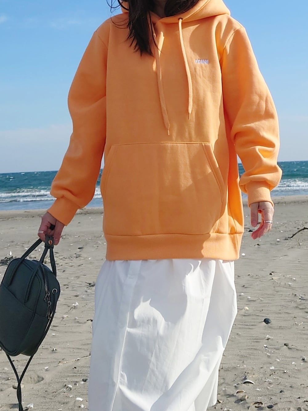 オレンジ系のパーカー、グリーン系のショルダーバッグ、ホワイト系のワンピース/ドレスを着用したレディースの春コーディネートの4枚目の写真