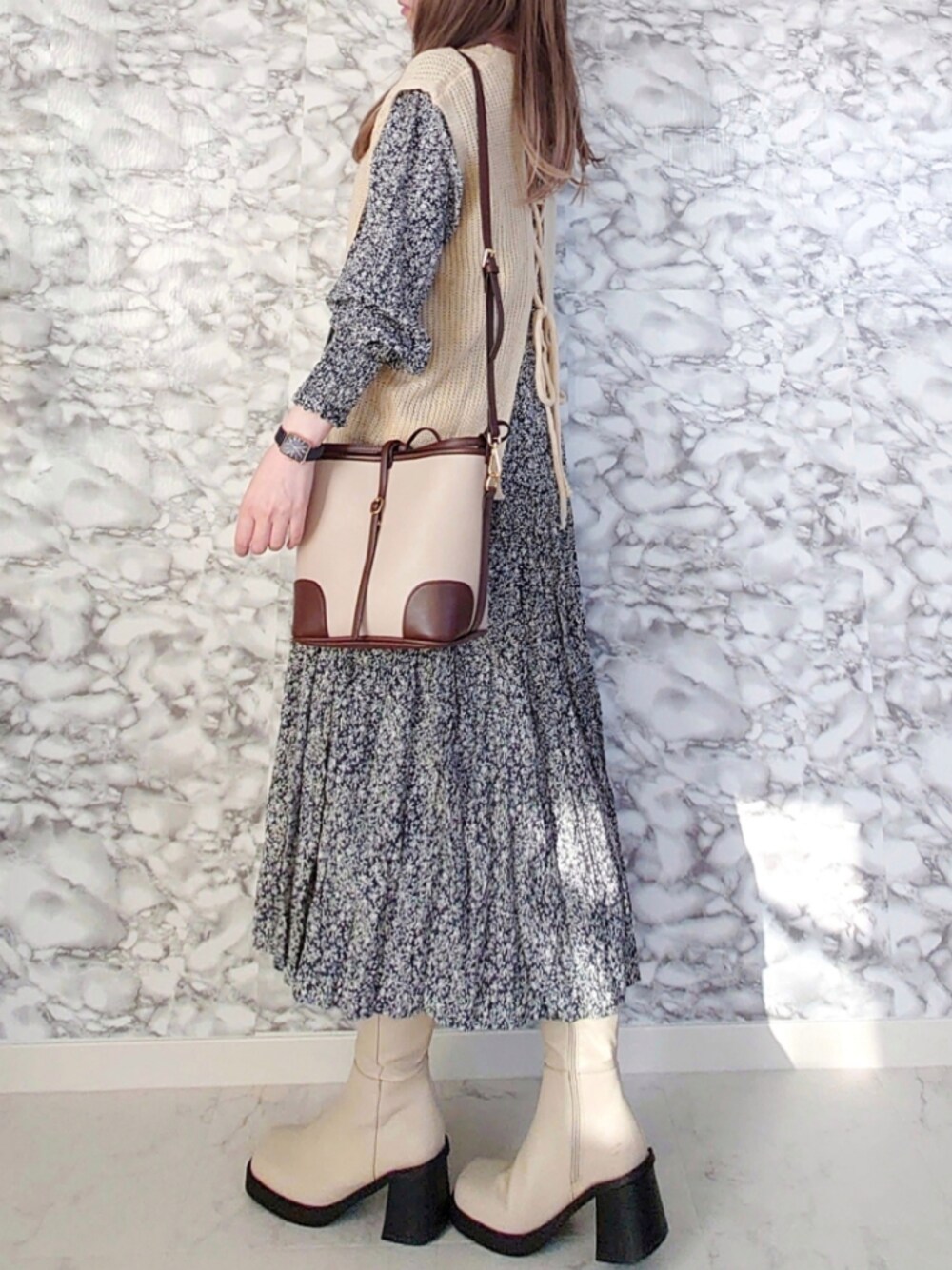 ブルー系のワンピース、ベージュ系のベスト、ホワイト系のショルダーバッグを着用したレディースの秋コーディネートの1枚目の写真