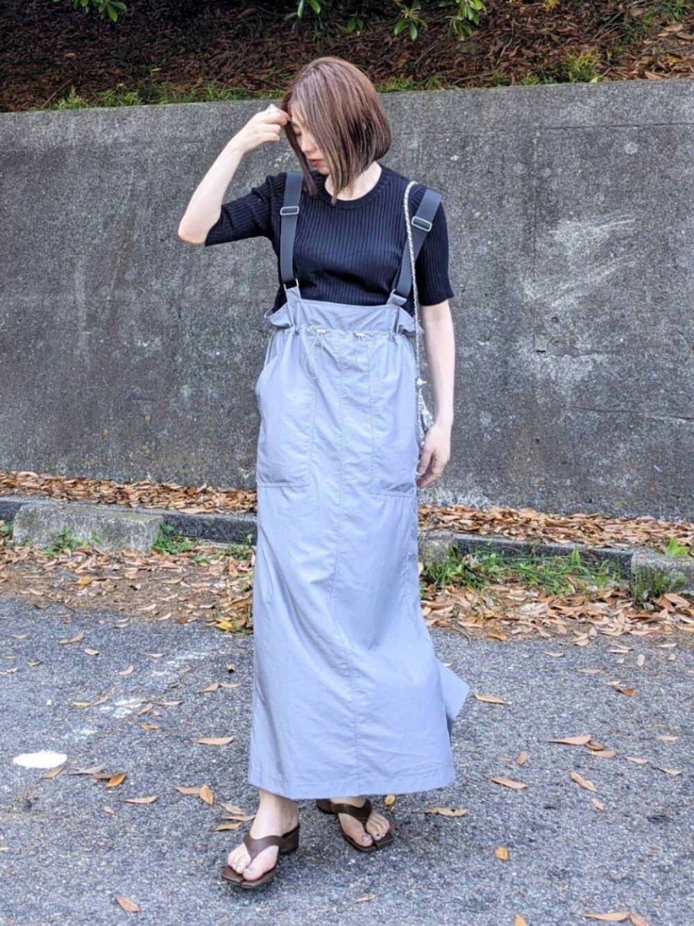 ブラック系のニット/セーター、グレー系のジャンパースカート、ブラウン系のサンダルを着用したレディースの夏コーディネートの1枚目の写真