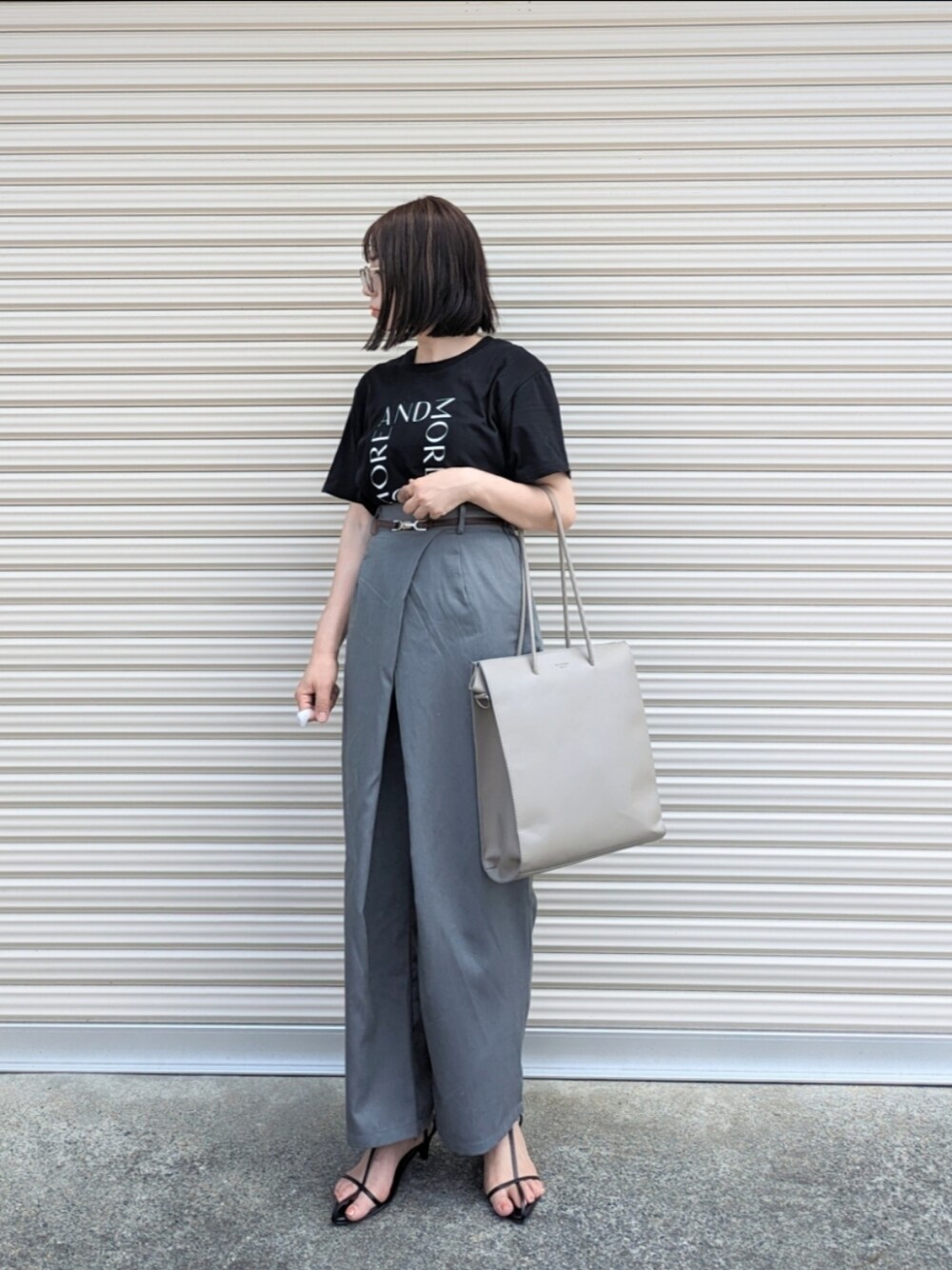 ブラック系のTシャツ/カットソー、グレー系のスラックス、グレー系のトートバッグを着用したレディースの夏コーディネートの1枚目の写真