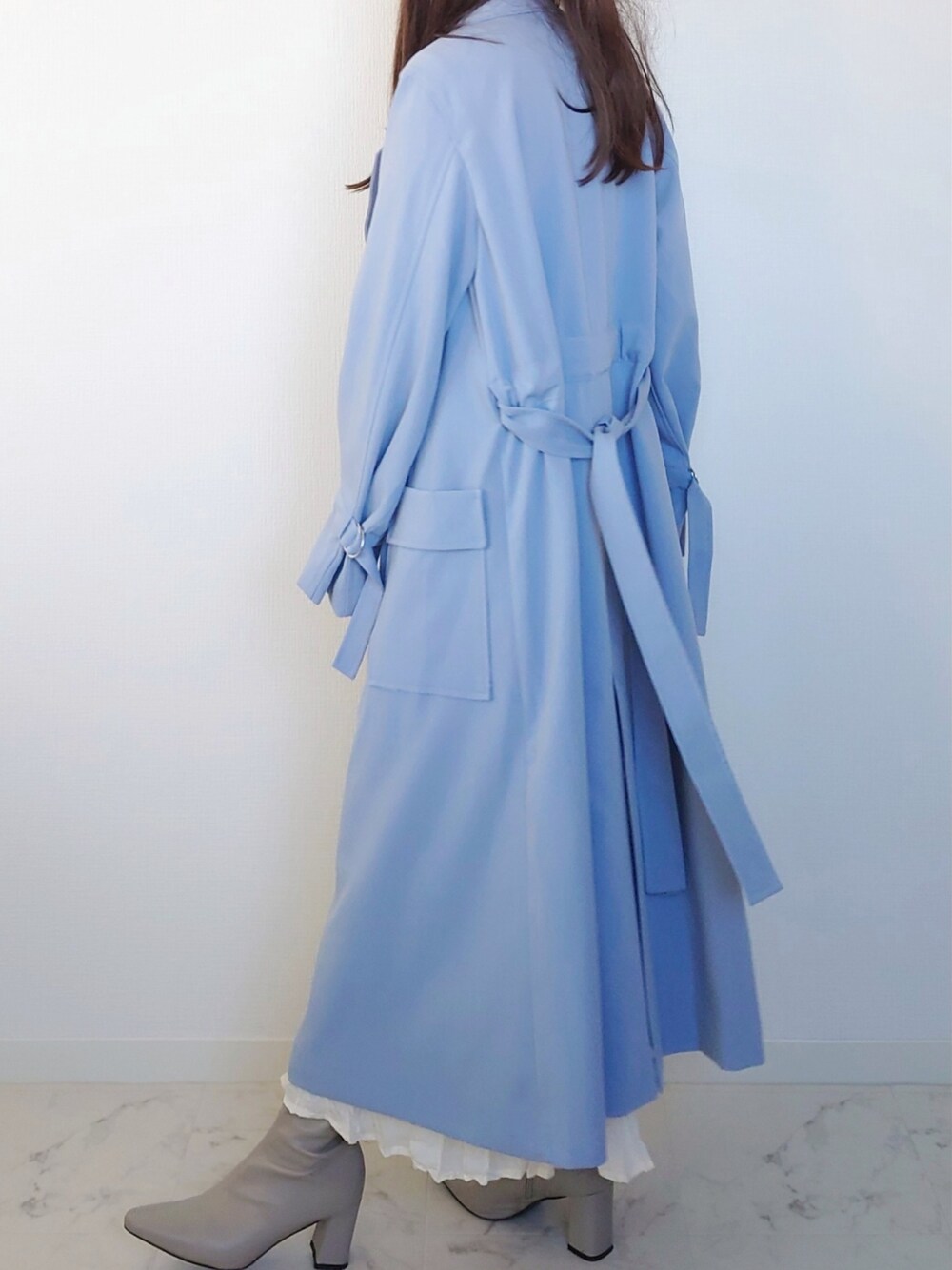 ホワイト系のワンピース、ブルー系のトレンチコート、ベージュ系のボストンバッグを着用したレディースの春コーディネートの2枚目の写真