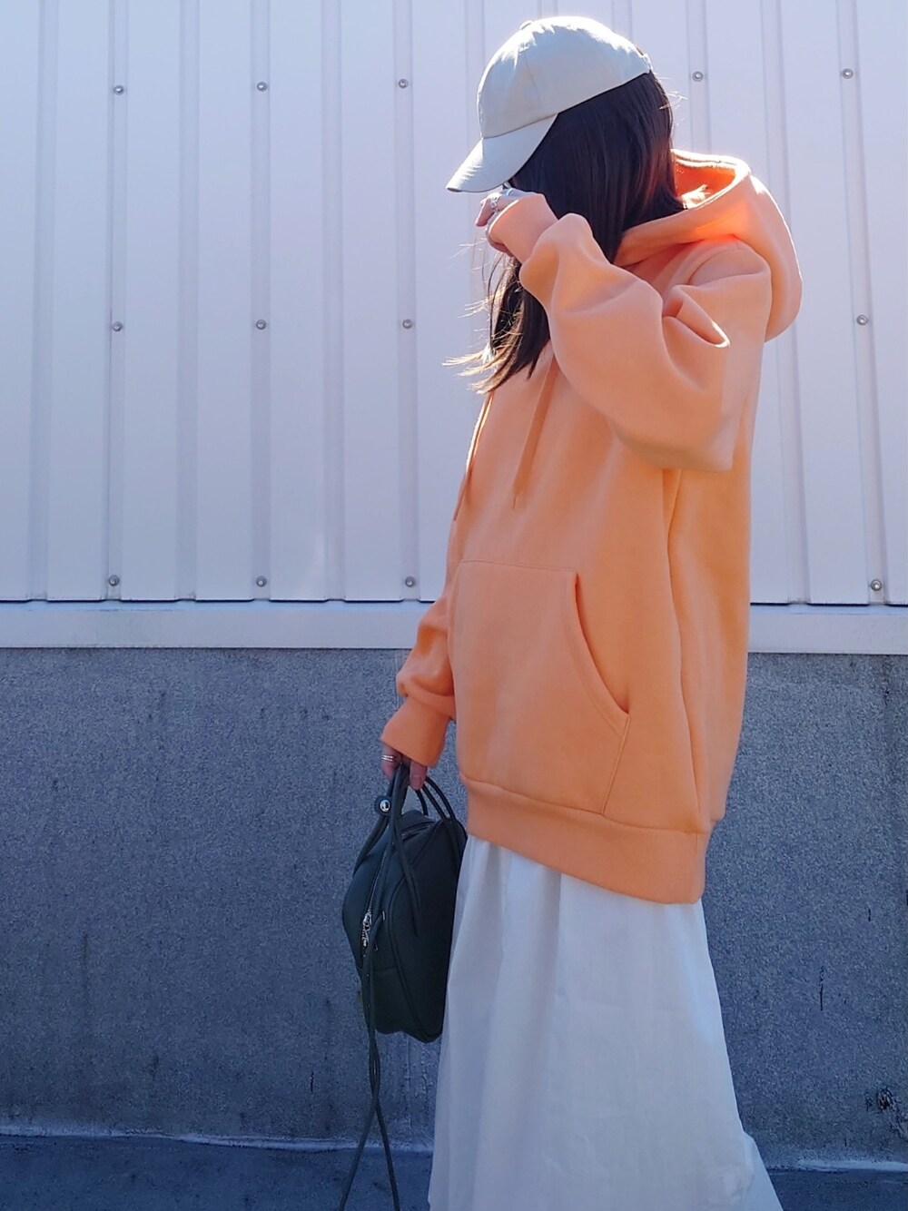 オレンジ系のパーカー、グリーン系のショルダーバッグ、ホワイト系のワンピース/ドレスを着用したレディースの春コーディネートの2枚目の写真