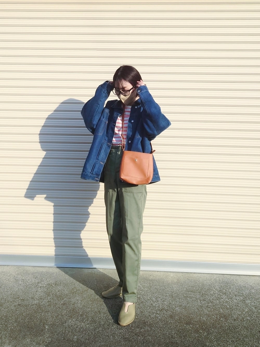 グリーン系のチノパンツ、ブラウン系のショルダーバッグ、グリーン系のパンプスを着用したレディースの冬コーディネートの1枚目の写真