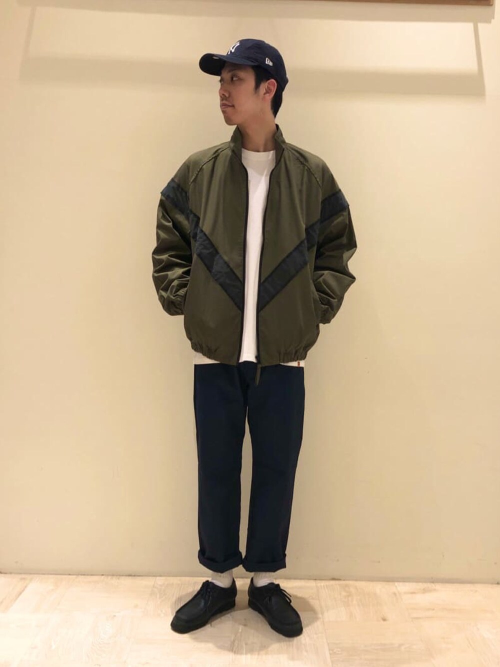 グリーン系のブルゾン、ホワイト系のTシャツ/カットソー、ブラック系のチノパンツを着用したメンズの冬コーディネートの1枚目の写真