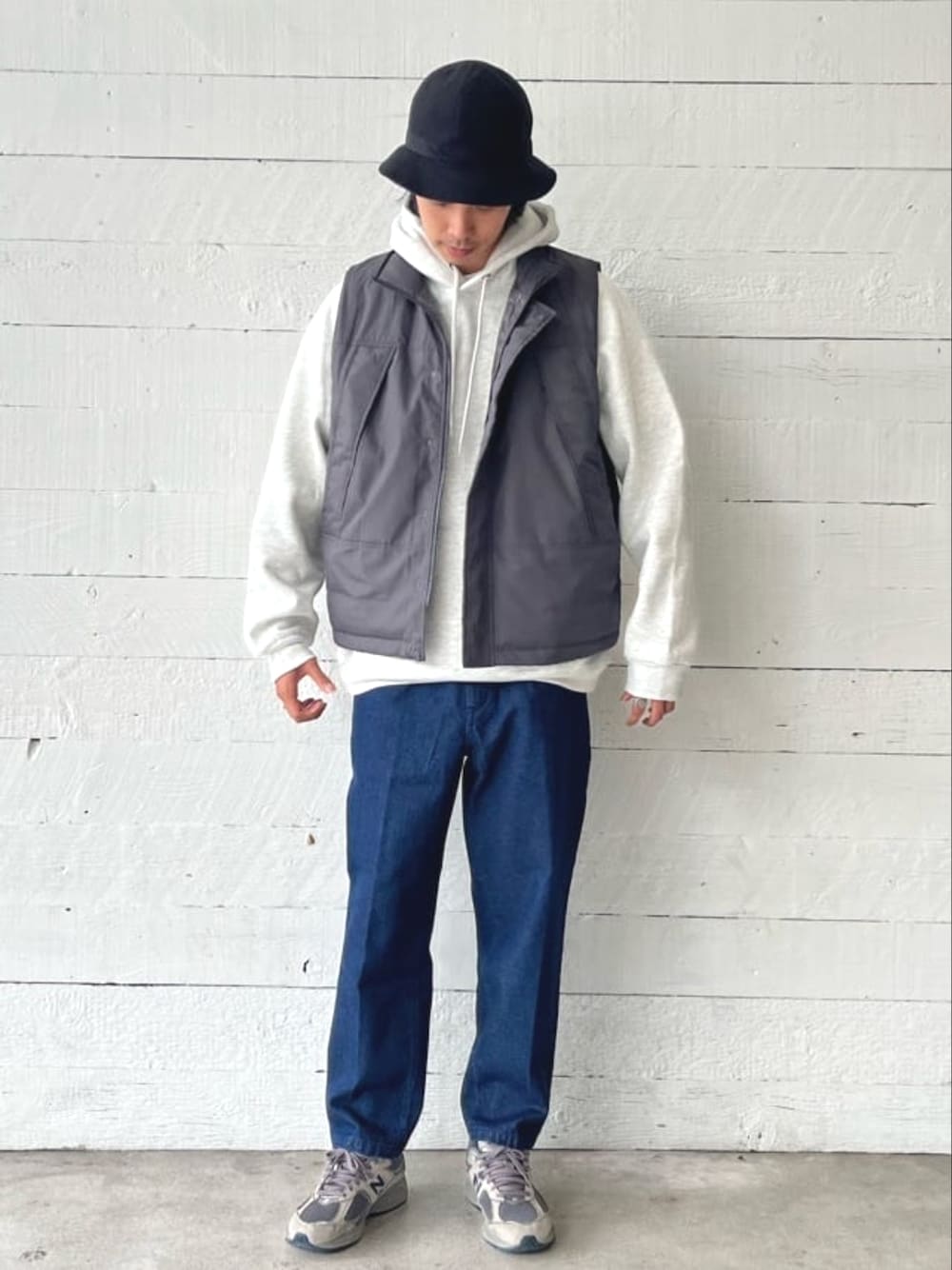 グレー系のパーカー、グレー系のダウンベスト、ブルー系のその他パンツを着用したメンズの秋コーディネートの1枚目の写真