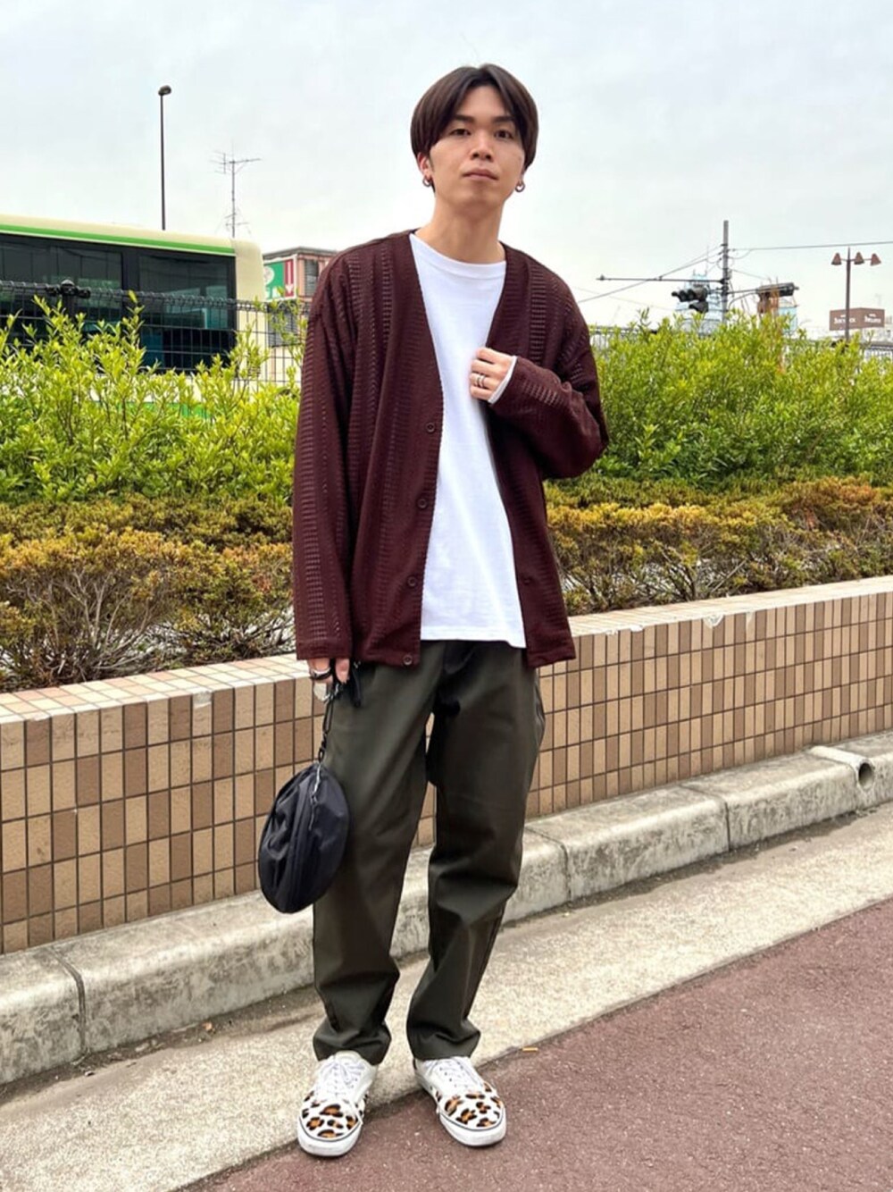 ブラウン系のカーディガン/ボレロ、ホワイト系のTシャツ/カットソー、グリーン系のチノパンツを着用したメンズの春コーディネートの1枚目の写真