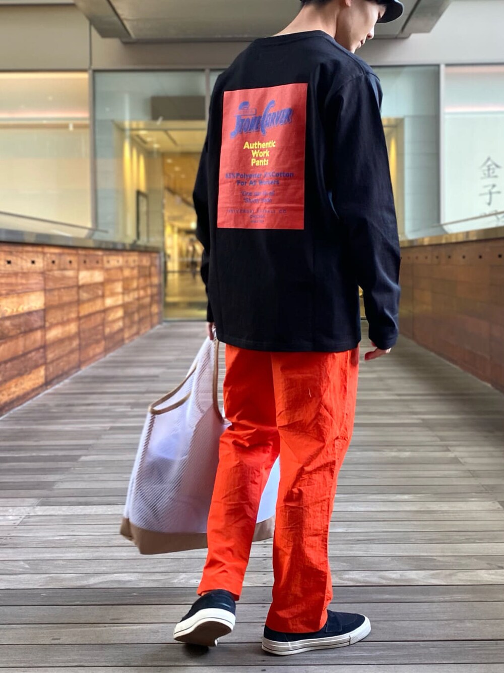 ブラック系のTシャツ/カットソー、オレンジ系のその他パンツ、ホワイト系のトートバッグを着用したメンズの春コーディネートの1枚目の写真
