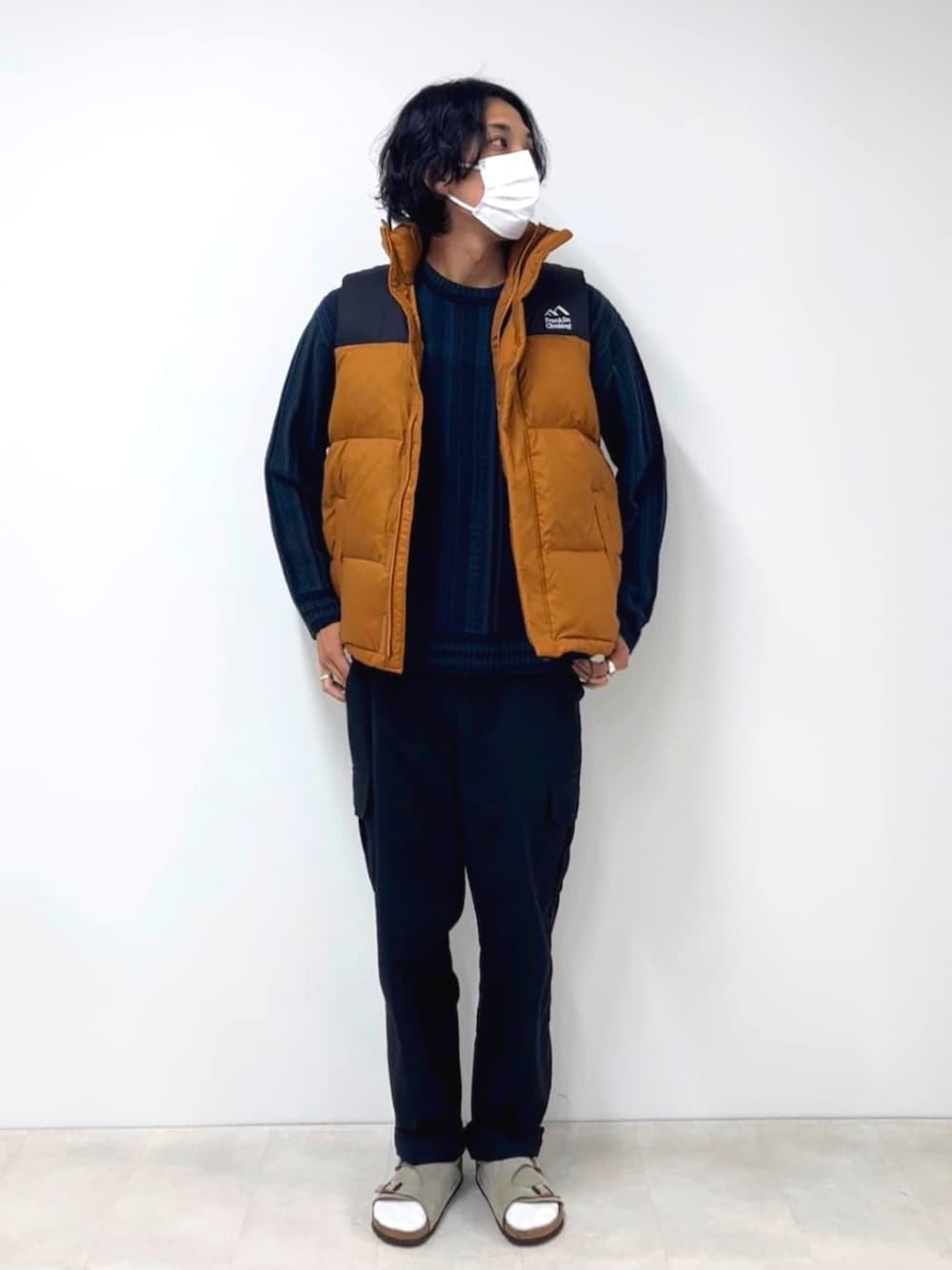 ブルー系のニット/セーター、イエロー系のダウンベストを着用したメンズの秋コーディネートの1枚目の写真