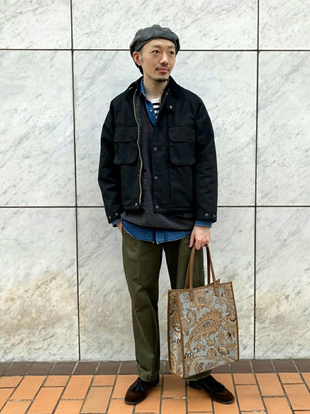 ブラック系のブルゾン、グレー系のベスト、ブラウン系のサンダルを着用したメンズの秋コーディネートの1枚目の写真