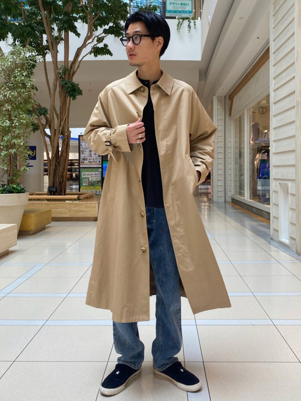 ベージュ系のステンカラーコート、ブラック系のTシャツ/カットソー、ブルー系のデニムパンツを着用したメンズの秋コーディネートの1枚目の写真