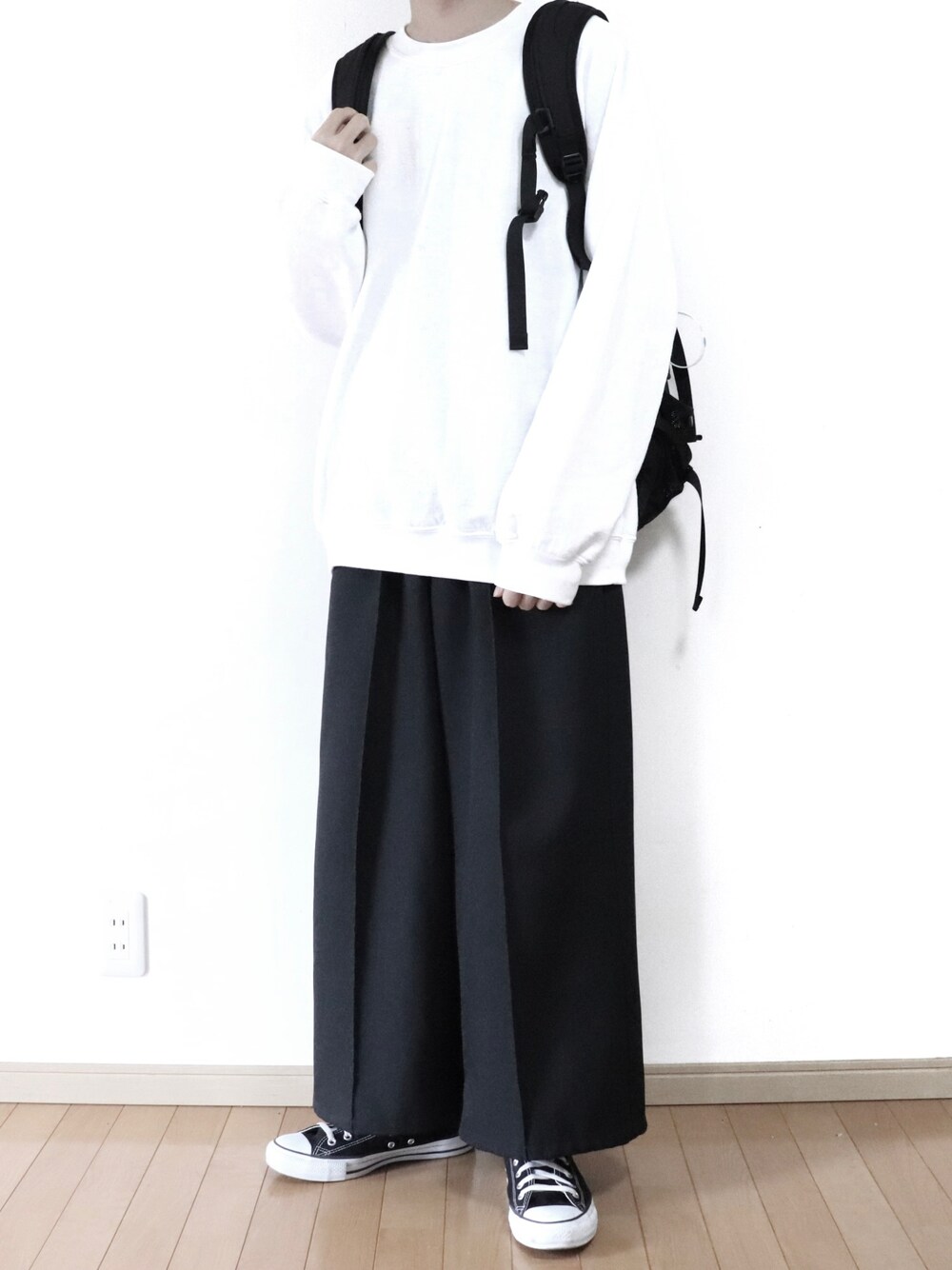 ホワイト系のスウェット、ブラック系のスラックス、ブラック系のスニーカーを着用したメンズの春コーディネートの1枚目の写真