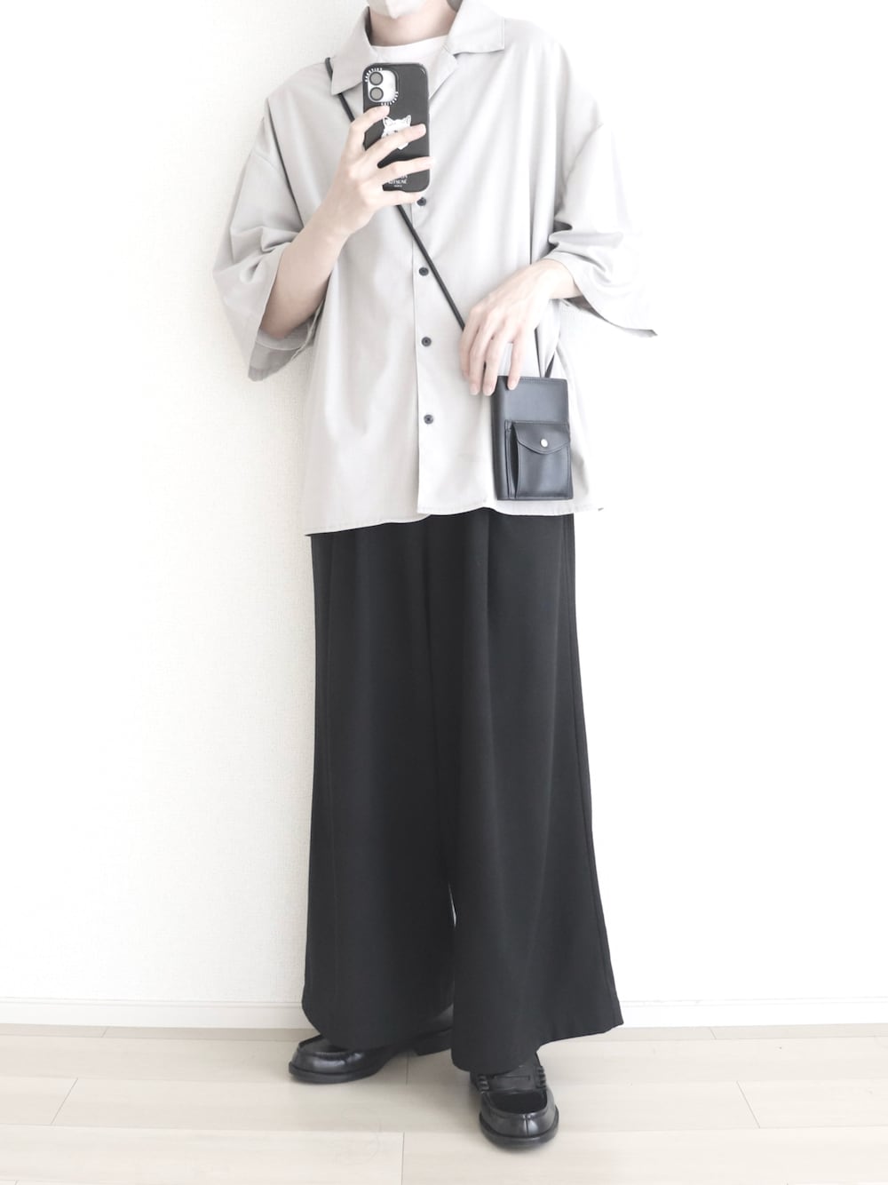 グレー系のTシャツ/カットソー、ブラック系のスラックス、ブラック系のショルダーバッグを着用したメンズの秋コーディネートの1枚目の写真