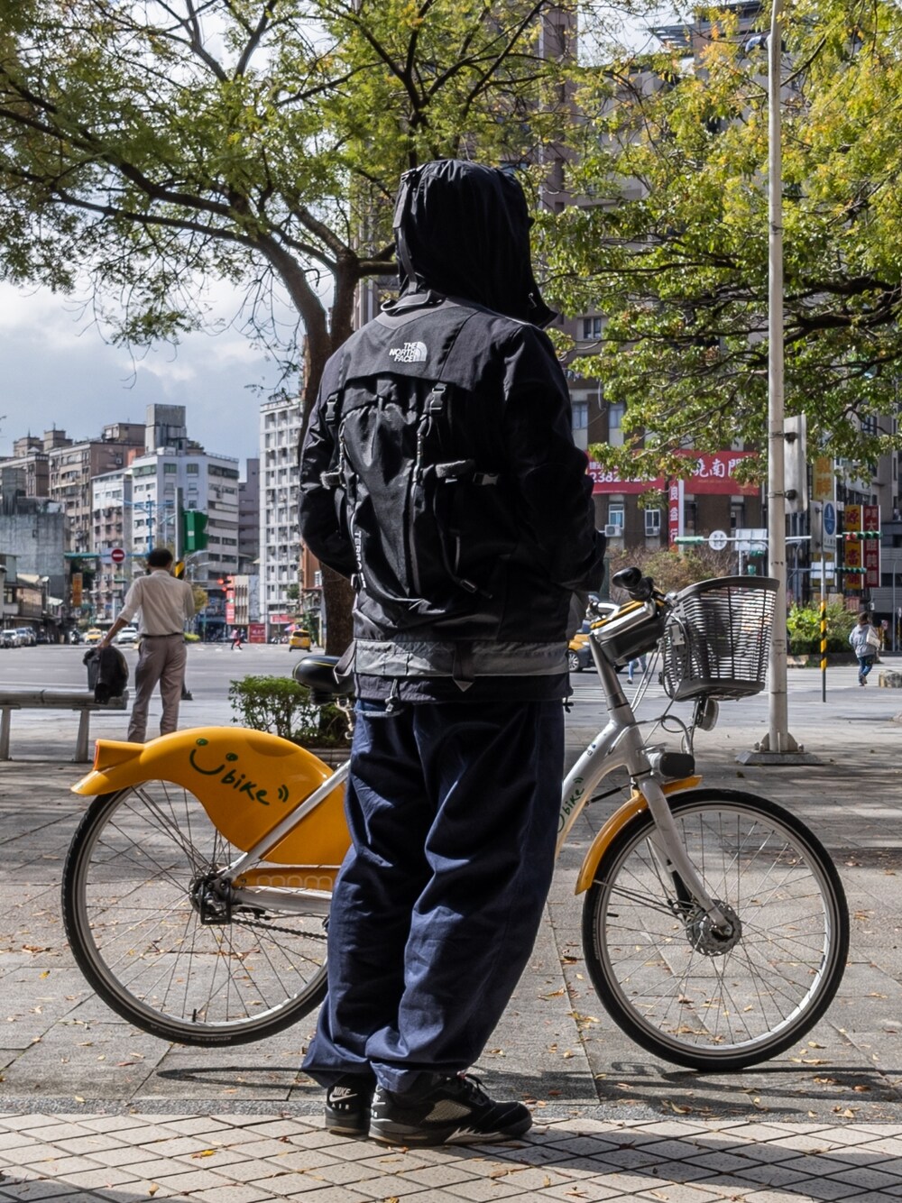 ブラック系のマウンテンパーカー、ブルー系のパンツ、ブラック系のスニーカーを着用したメンズの冬コーディネートの1枚目の写真