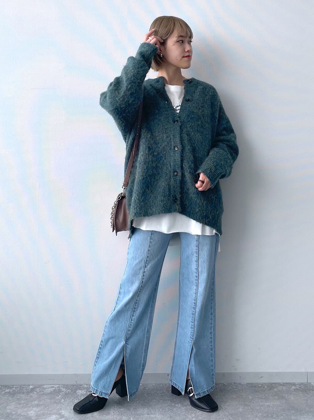 ブルー系のデニムパンツ、ホワイト系のTシャツ/カットソー、グリーン系のニット/セーターを着用したレディースの秋コーディネートの1枚目の写真