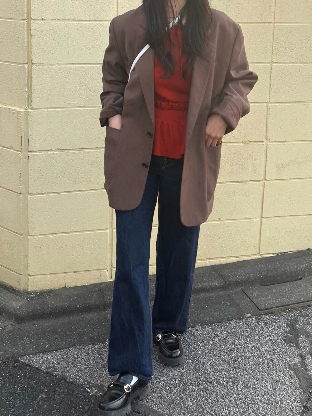 オレンジ系のニット/セーター、ブラウン系のテーラードジャケットを着用したレディースの春コーディネートの1枚目の写真