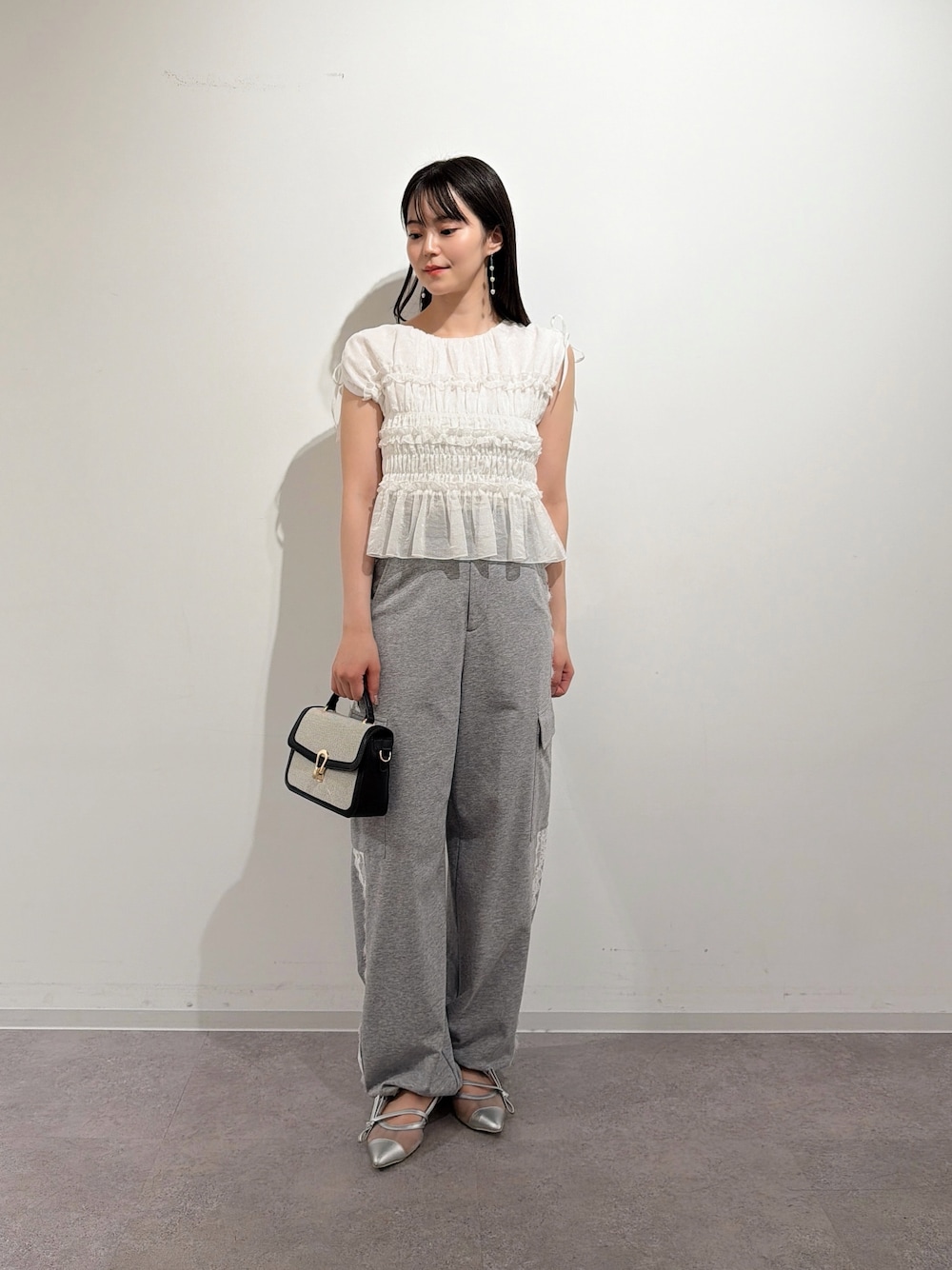 ホワイト系のシャツ/ブラウス、シルバー系のパンプス、ブラック系のショルダーバッグを着用したレディースの夏コーディネートの1枚目の写真
