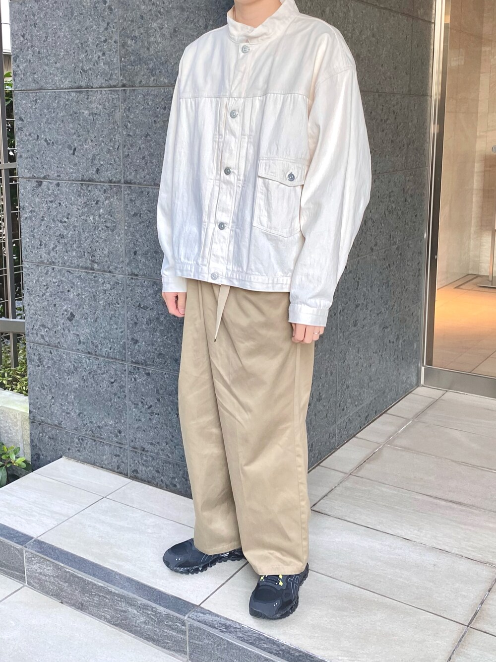 ホワイト系のブルゾン、グリーン系のチノパンツ、ブラック系のスニーカーを着用したメンズの秋コーディネートの1枚目の写真