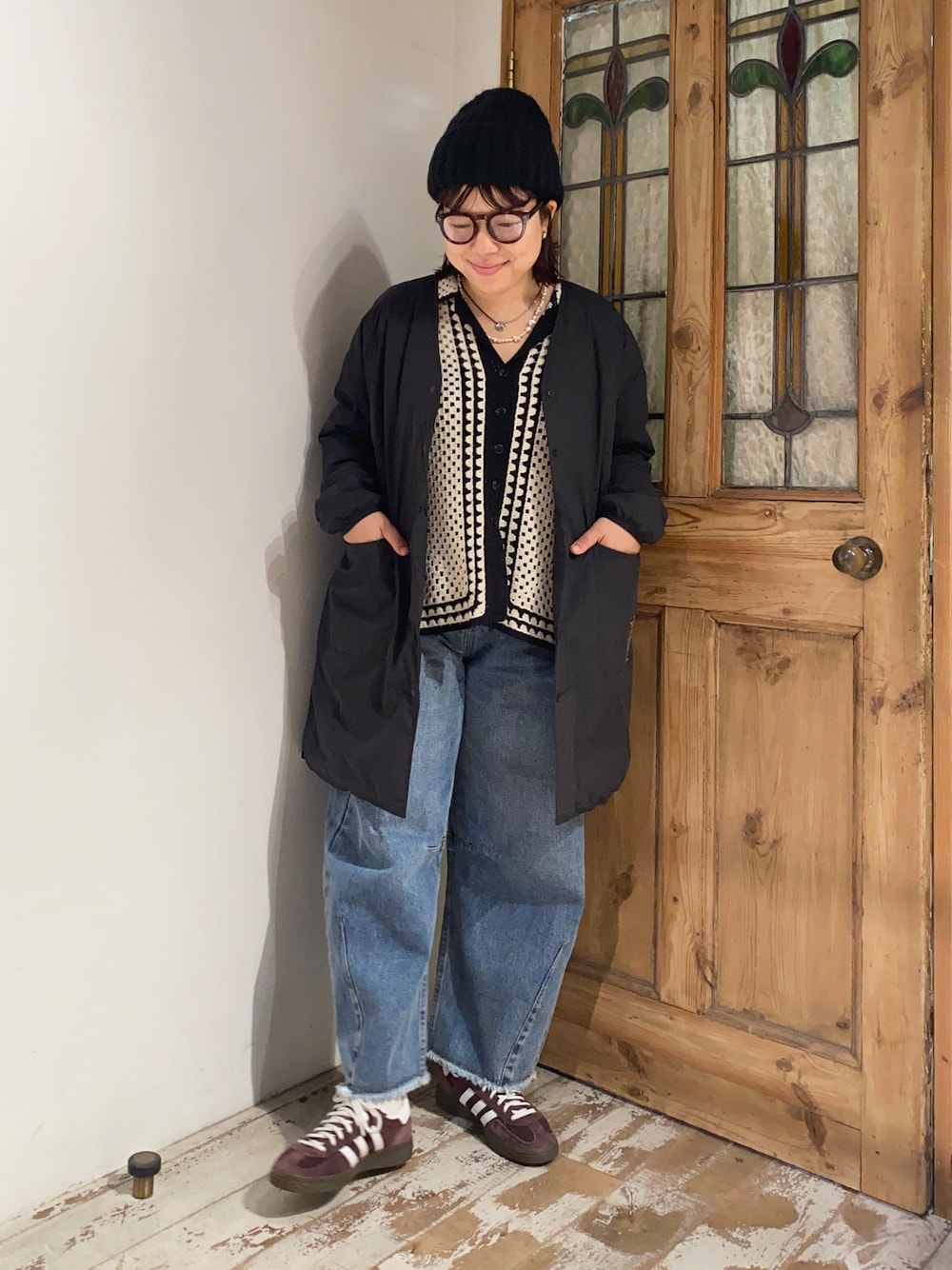 ホワイト系のカーディガン/ボレロ、ブラック系のダウンジャケット/コート、ブルー系のデニムパンツを着用したレディースの秋コーディネートの1枚目の写真