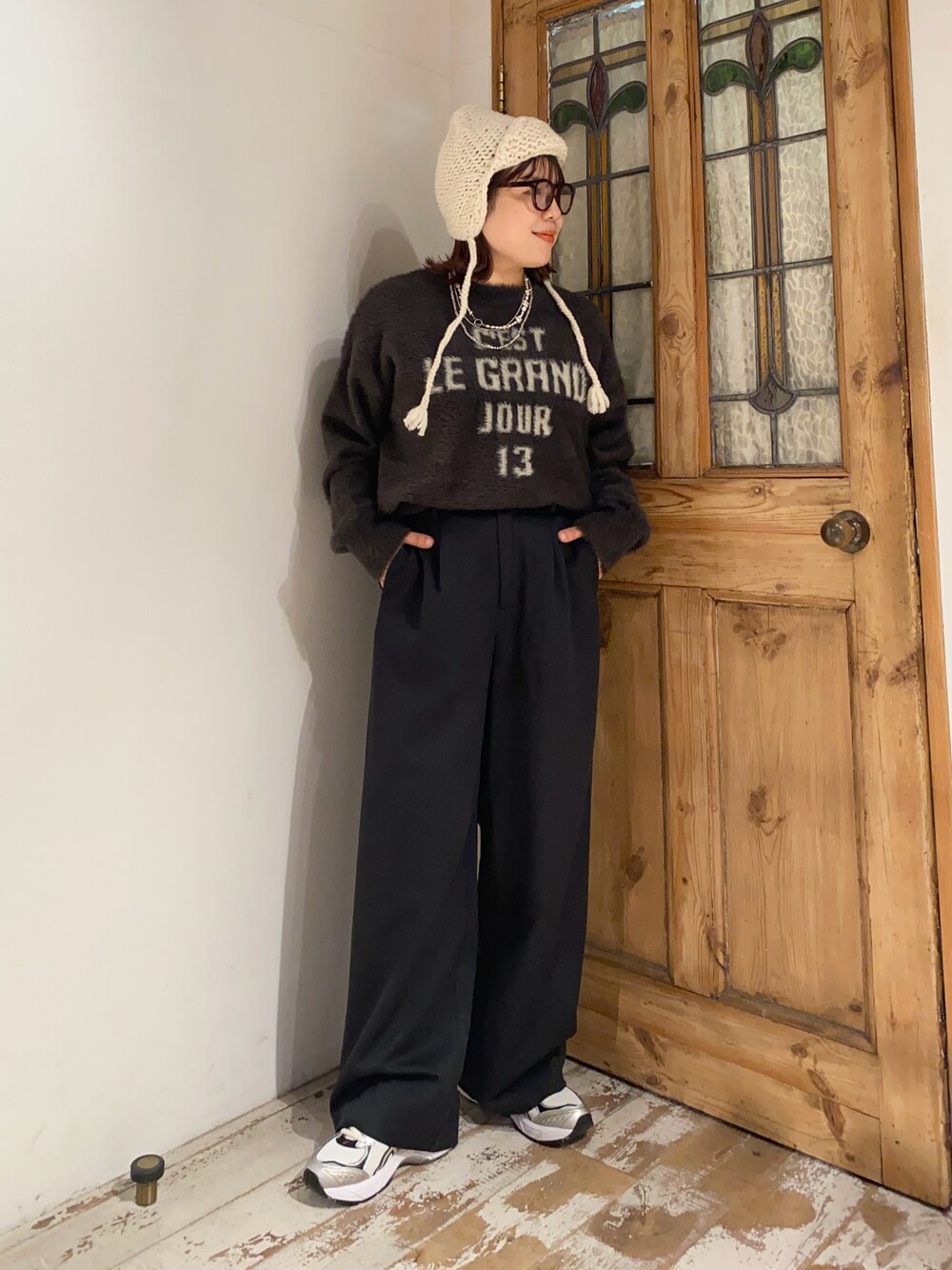 ブラウン系のニット/セーター、ブラック系のスラックス、ホワイト系のスニーカーを着用したレディースの冬コーディネートの1枚目の写真