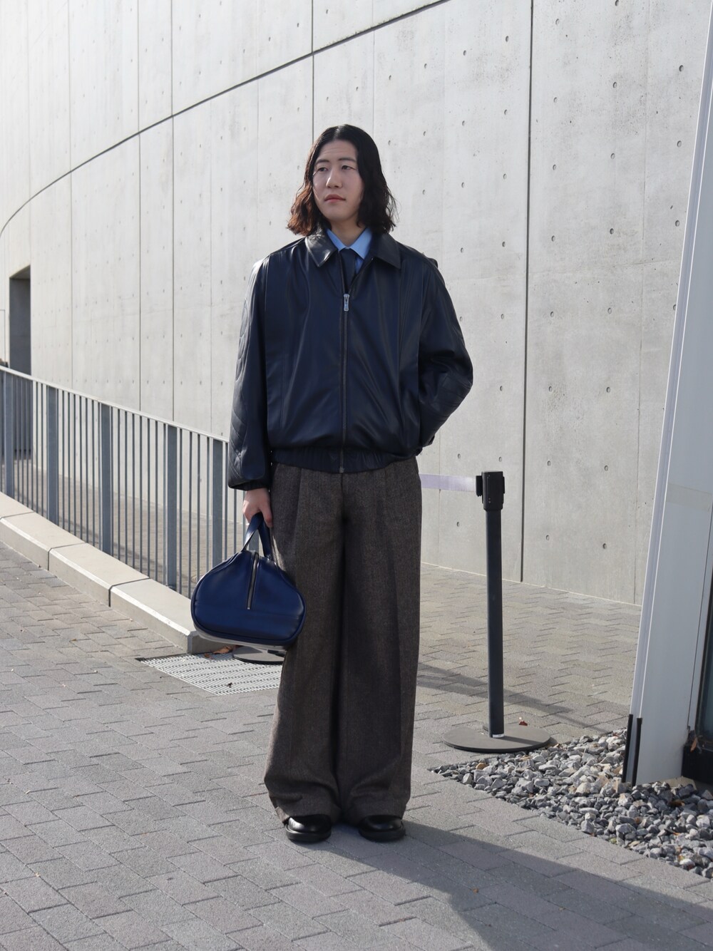 ブルー系のジャケット/アウター、グレー系のスラックス、ブルー系のボストンバッグを着用したメンズの冬コーディネートの1枚目の写真