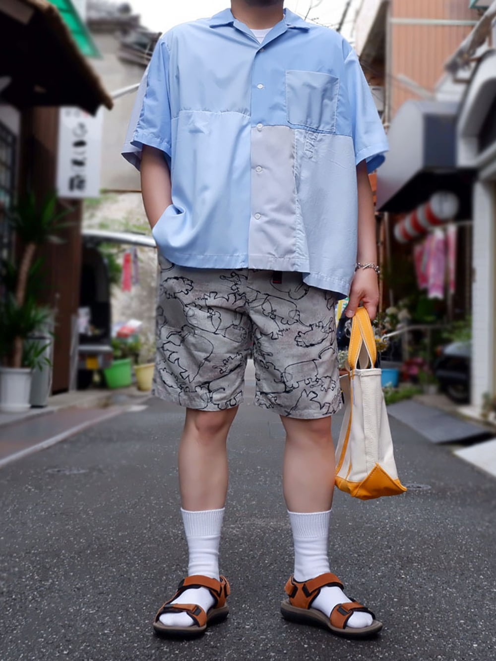 ブルー系のシャツ/ブラウス、ベージュ系のトートバッグ、グレー系のパンツを着用したメンズの春コーディネートの1枚目の写真