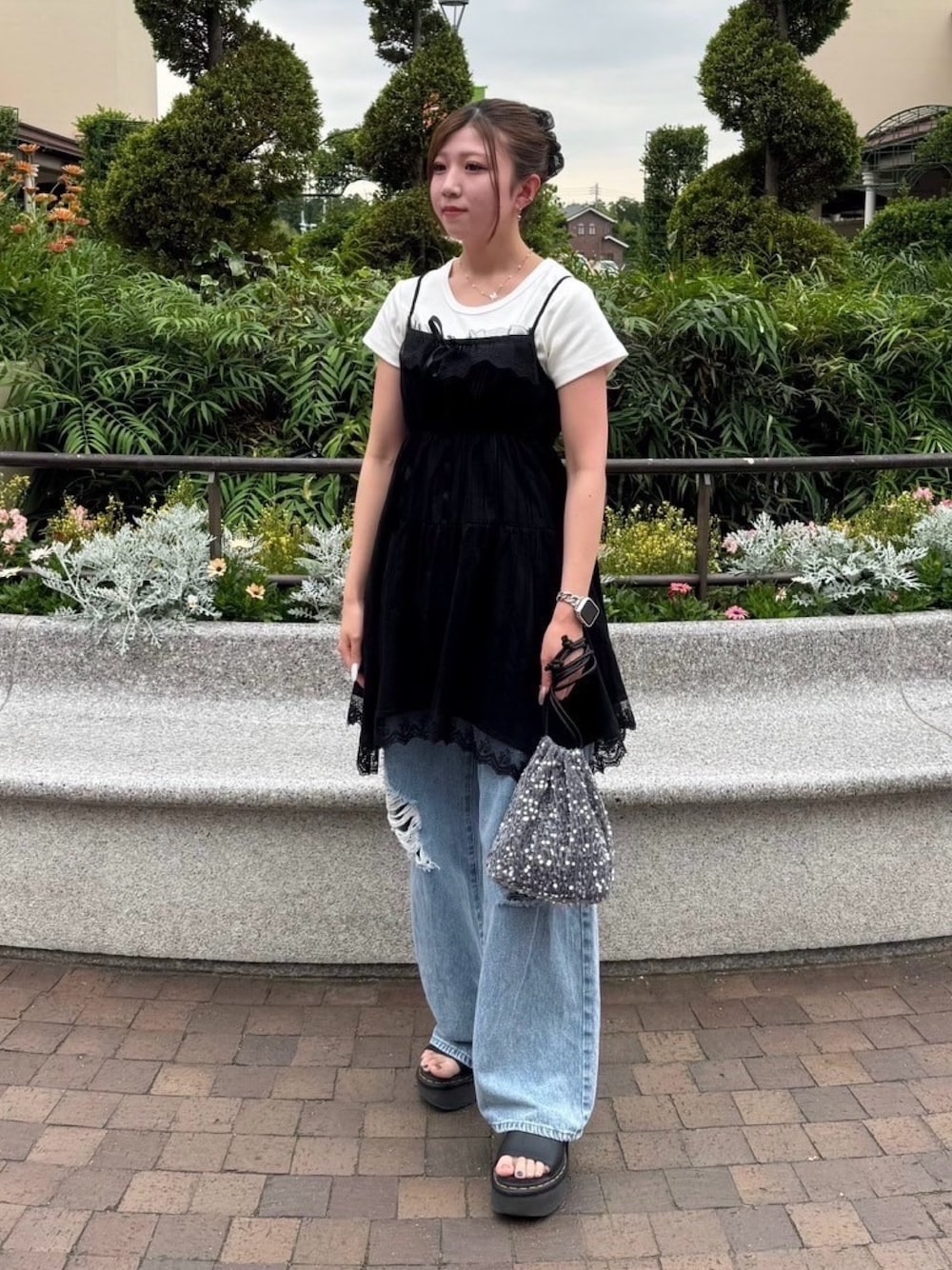 ブラック系のチュニック、ブルー系のデニムパンツ、シルバー系のショルダーバッグを着用したレディースの夏コーディネートの1枚目の写真