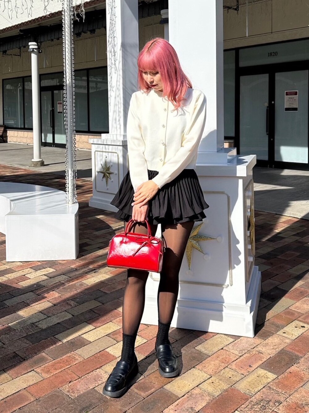ホワイト系のカーディガン/ボレロ、ブラック系のその他パンツ、レッド系のボストンバッグを着用したレディースの春コーディネートの1枚目の写真
