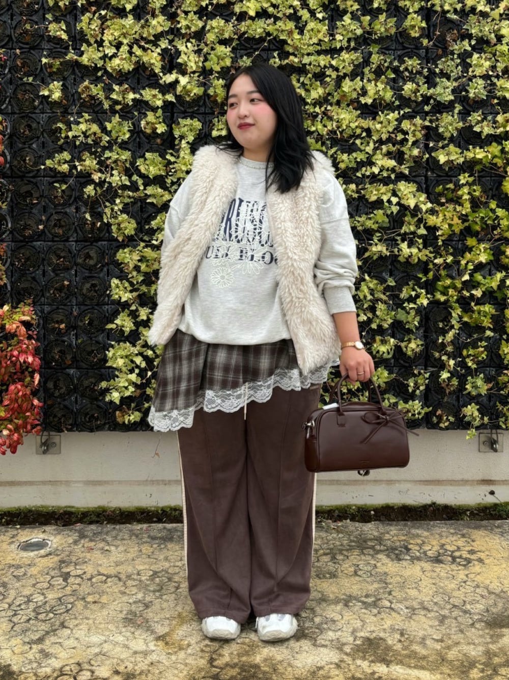 ブラウン系のスラックス、ブラウン系のチュニック、ホワイト系のベストを着用したレディースの秋コーディネートの1枚目の写真