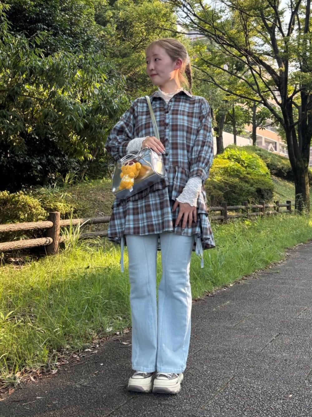 ブラウン系のチュニック、ブルー系のデニムパンツ、イエロー系のキーホルダーを着用したレディースの秋コーディネートの1枚目の写真