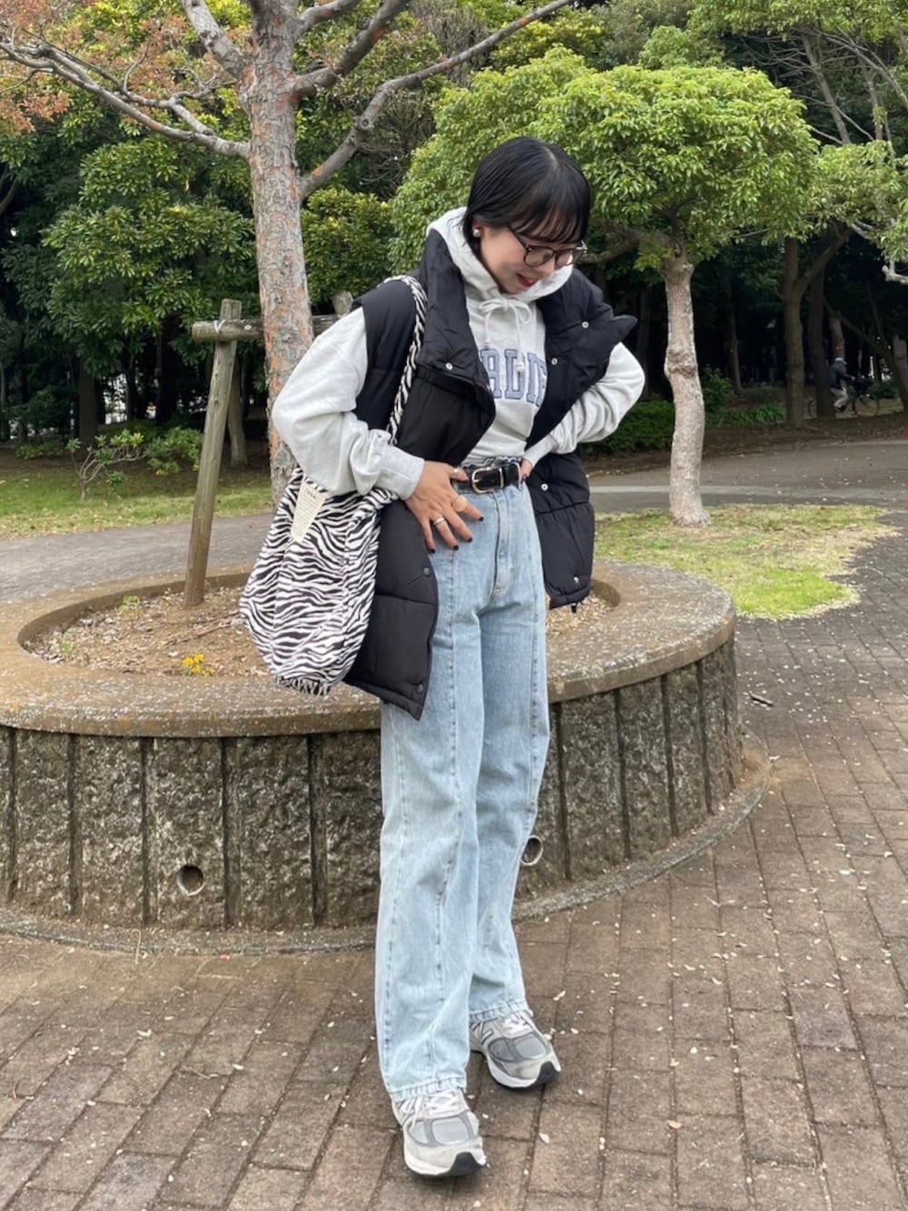 ブルー系のデニムパンツ、その他のトートバッグ、ブラック系のダウンベストを着用したレディースの秋コーディネートの1枚目の写真