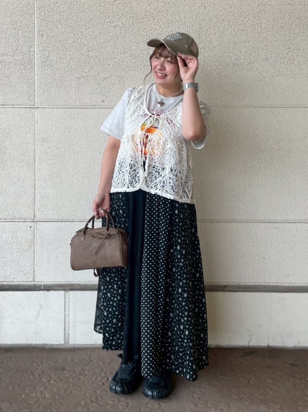 ブラック系のスカート、ベージュ系のTシャツ/カットソー、ベージュ系のベストを着用したレディースの夏コーディネートの1枚目の写真