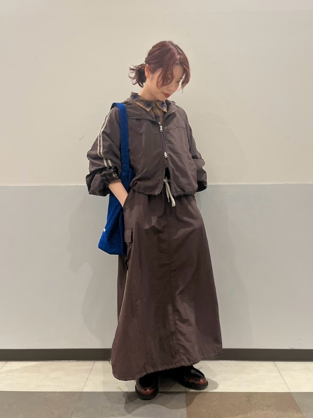 ブラウン系のブルゾン、ブラウン系のスカート、ブルー系のトートバッグを着用したレディースの秋コーディネートの1枚目の写真