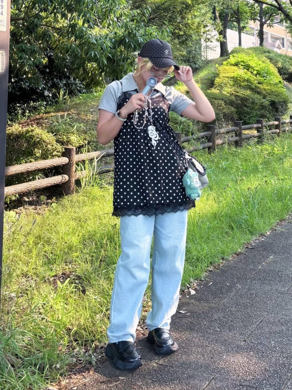 ブラック系のチュニック、ブルー系のデニムパンツ、ブラック系のローファーを着用したレディースの夏コーディネートの1枚目の写真