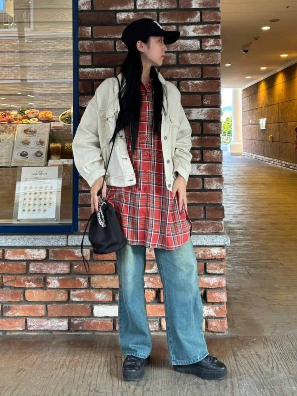 レッド系のチュニック、ブルー系のデニムパンツ、ホワイト系のデニムジャケットを着用したレディースの秋コーディネートの1枚目の写真